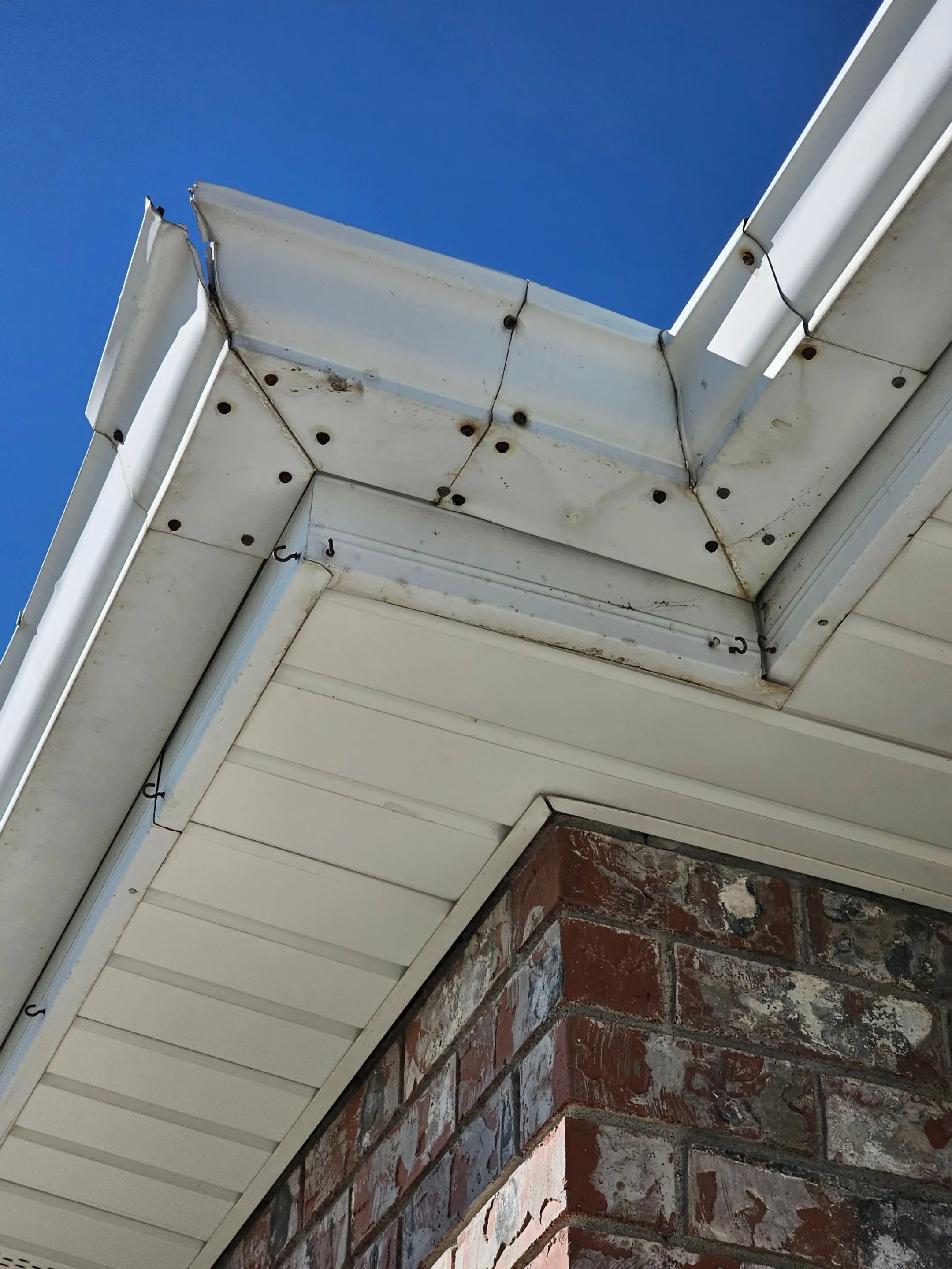 A white gutter corner with a visible gap beneath the roofline