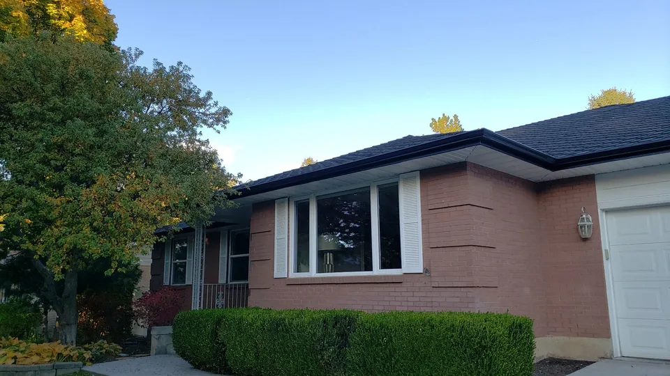 Dark gutters along the roofline of a brick home