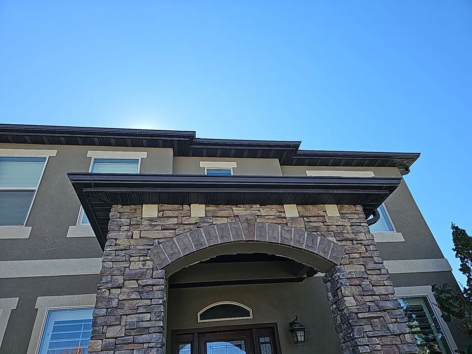 Dark gutters tracing the roofline above a stone entry