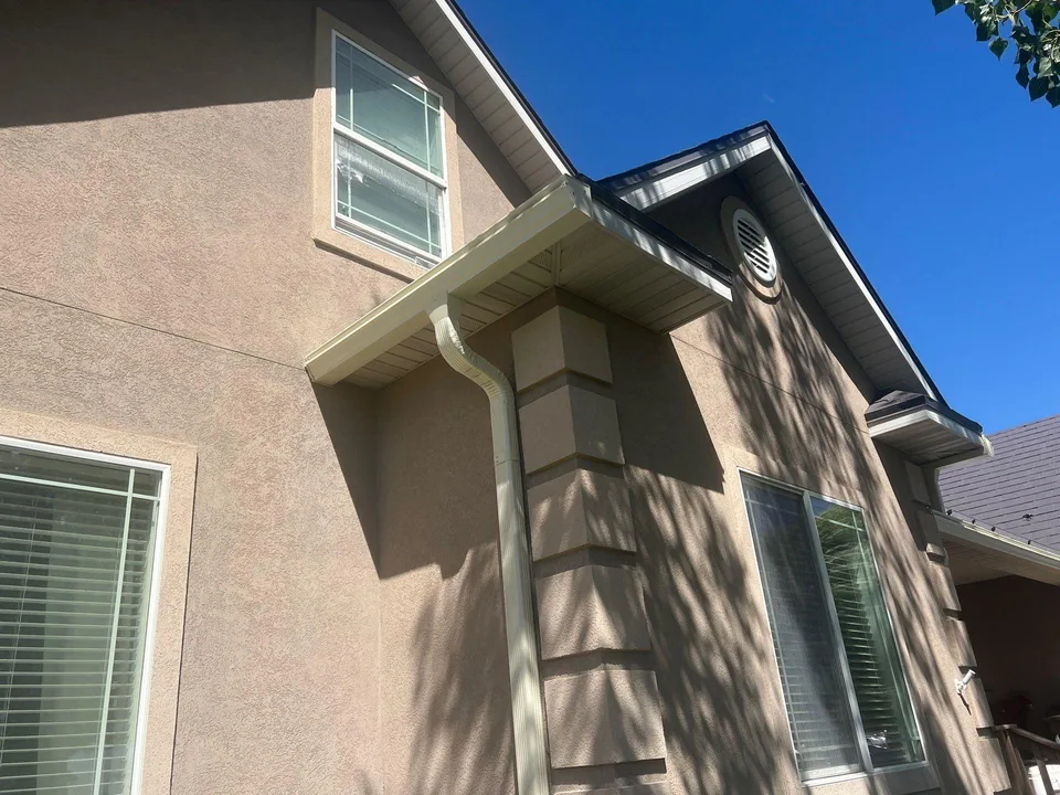 White gutter and downspout installed on a tan stucco home