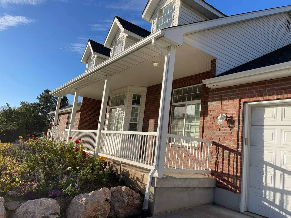 White gutters and downspouts along a brick home's covered porch