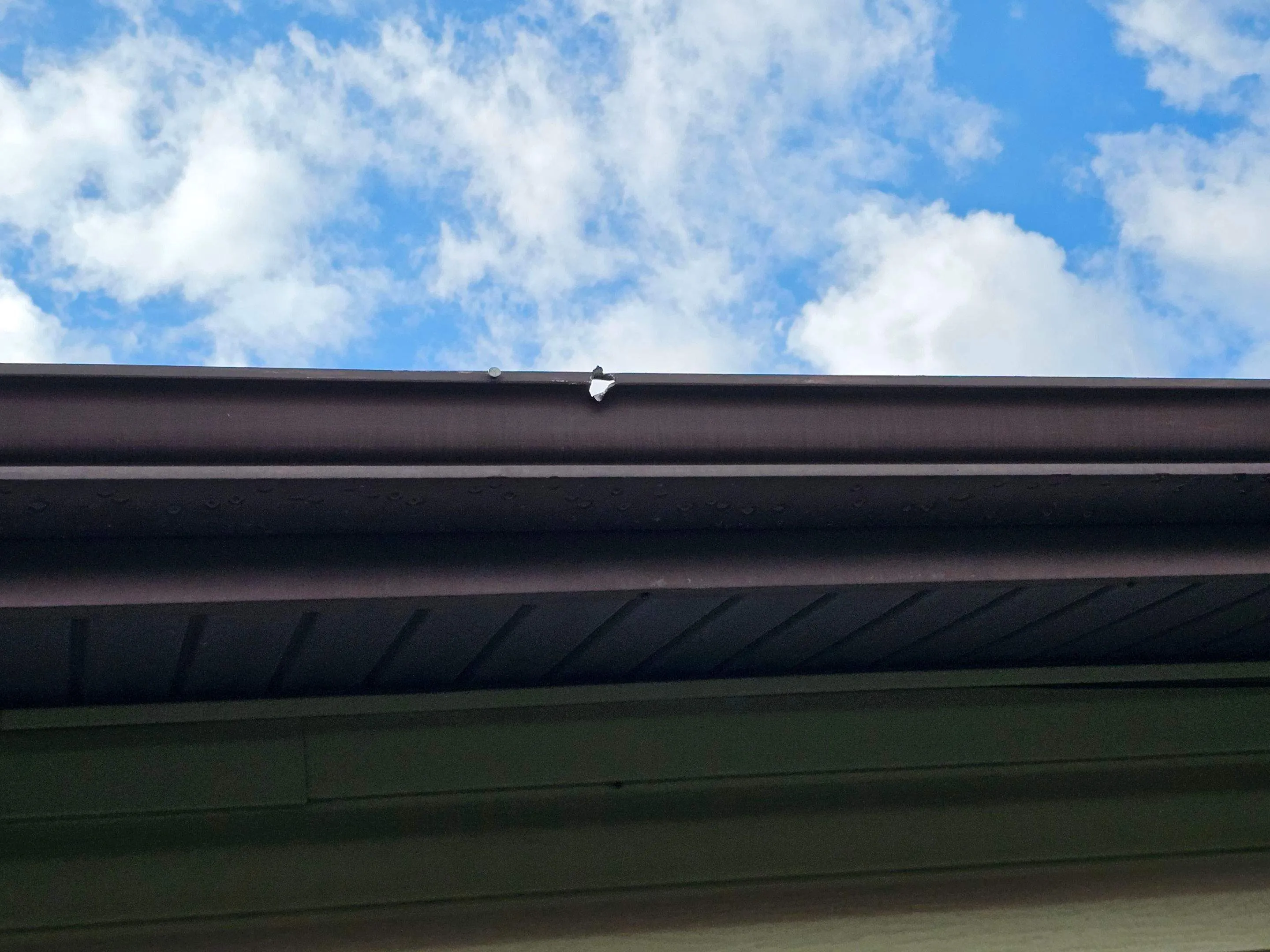 Close view of a covered white Gutter Shutter system at a roof corner