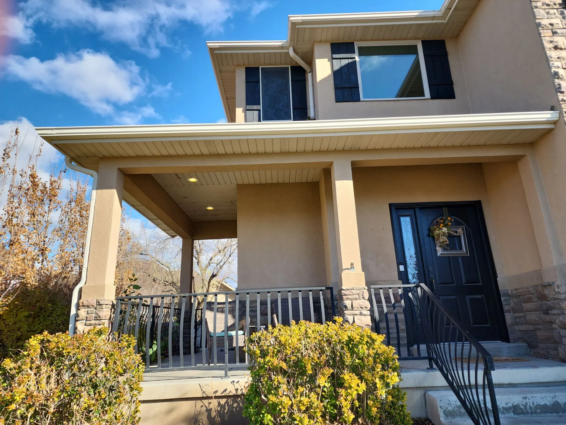 White gutter and downspout along the roofline of a stucco home